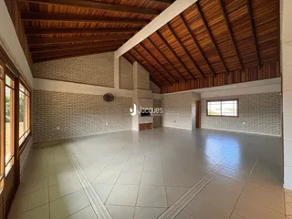 Interior de uma sala ampla com teto de madeira e paredes de tijolo aparente.
