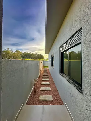 Vista lateral de um pátio com caminho de pedras e cascalho em uma residência.