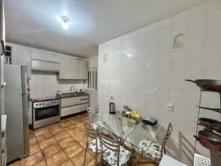 Cozinha com piso de cerâmica e armários brancos em imóvel no Brasil.
