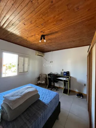 Quarto com cama e teto de madeira aparente.