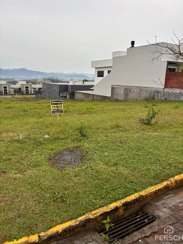 Fachada de uma residência moderna em Lajeado, Brasil, com área gramada em primeiro plano.