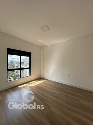 Ambiente interno com piso de madeira e grande janela de vista para a cidade.