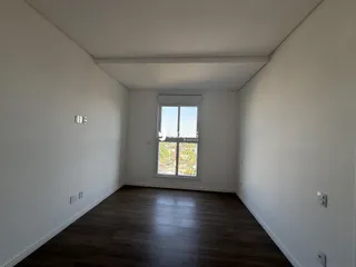 Ambiente interno de uma sala com piso de madeira escura.