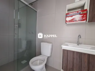 Foto de um banheiro com box de vidro e bancada de madeira.