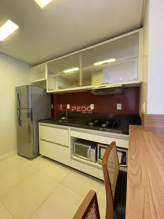 Foto da cozinha moderna com armários brancos e bancada escura.