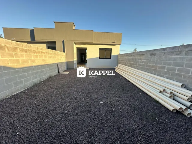 Fachada externa de uma residência em Lajeado, Brasil, com pátio de cascalho e tubulações visíveis.
