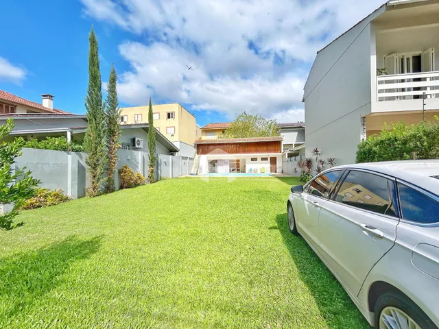 Jardim verde com árvores altas em frente a residências em Lajeado.