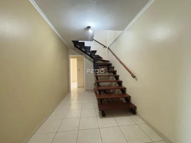 Corredor interno com piso de cerâmica e escadaria.
