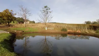 Paisagem de campo com água e vegetação ao fundo.