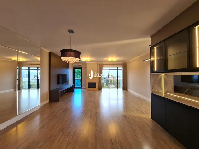 Sala de estar com piso de madeira clara e grandes janelas.