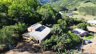 Vista aérea de uma propriedade rural com estruturas de celeiro e vegetação densa.