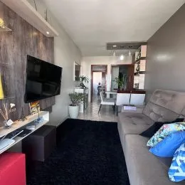 Sala de estar com sofá e televisão montada na parede.