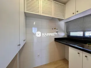 Cozinha moderna com armários brancos e bancada escura.