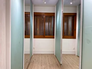 Hall de entrada com portas de madeira e piso de madeira clara.