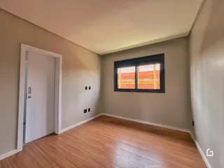 Vista interna de um corredor com piso de madeira e porta branca.