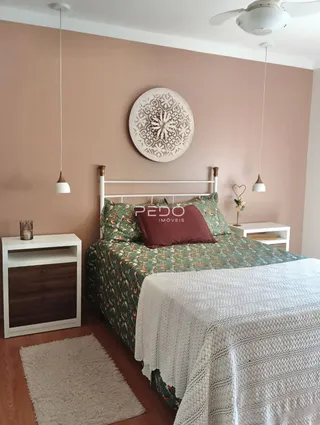 Quarto com cama de madeira e cabeceira decorativa.