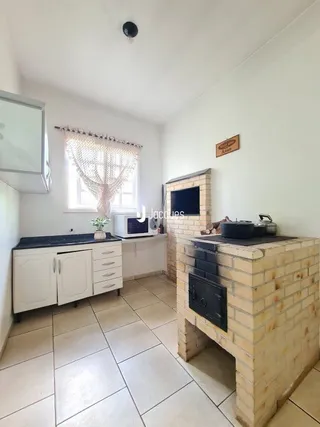 Interior de uma cozinha com piso de cerâmica e armários brancos.