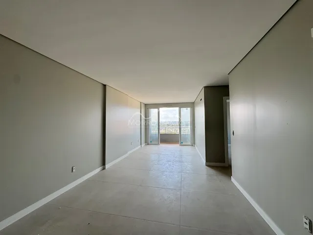Um corredor interno com piso claro e portas de vidro leva à vista externa.