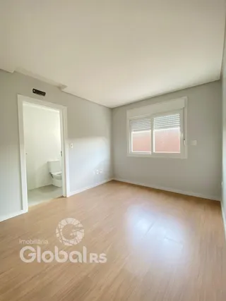Sala com piso de madeira clara e janela iluminada.