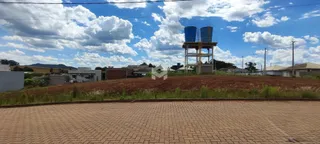 Vista externa de uma propriedade com terreno inclinado e estruturas ao fundo.