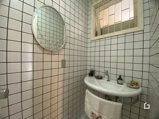 A foto mostra o interior de um banheiro com revestimento de azulejos brancos.