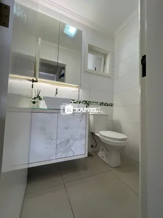 Banheiro com bancada de mármore e vaso sanitário branco.