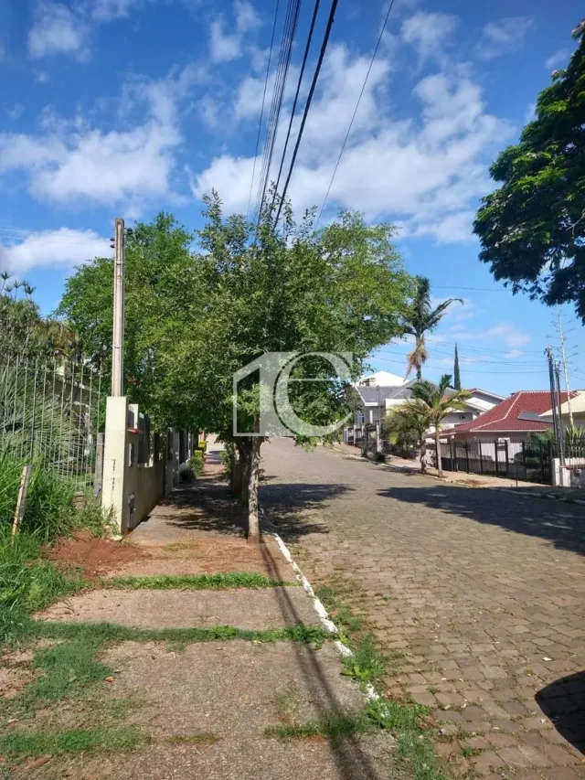 Vista externa de uma rua em Lajeado, Brasil, com vegetação e céu azul.