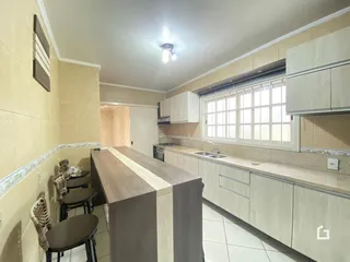 Vista interna de uma cozinha com armários e bancadas em tom claro.