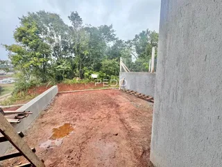 Vista externa de um terreno com solo de terra batida e muros de concreto.