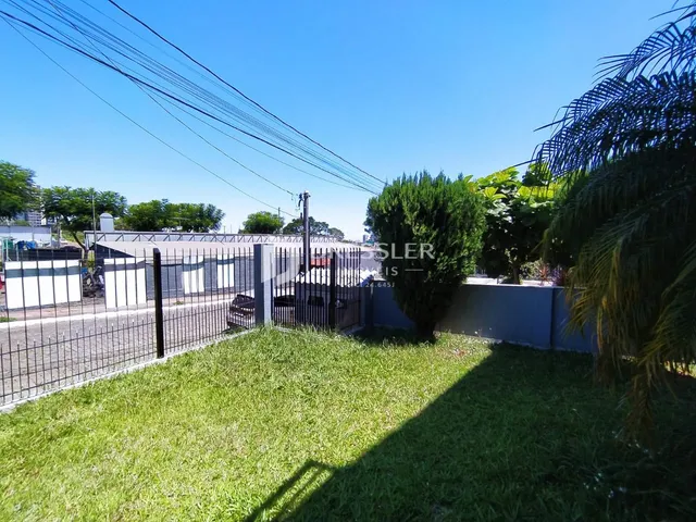 Vista externa de um quintal com cerca de metal e gramado verde.