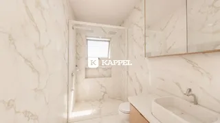 Foto de um banheiro com revestimento de mármore claro e bancada branca.