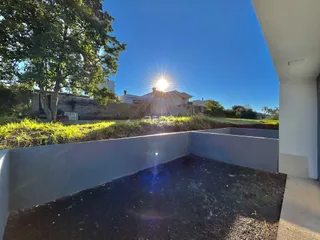 Vista externa de um terreno com muro baixo e vegetação.