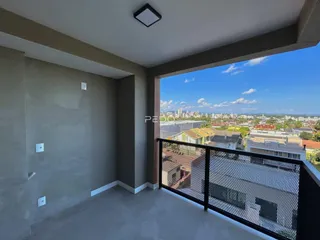 Vista de um ambiente interno com uma grande abertura para uma varanda com vista panorâmica da cidade.