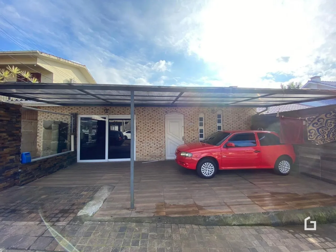 Fachada de casa com área coberta e carro estacionado.