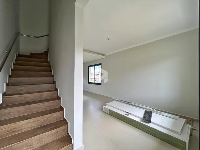 Vista de um corredor com escadaria de madeira em um imóvel.