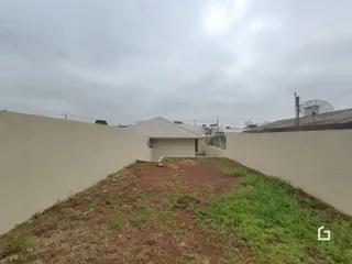 Parede alta de uma propriedade com grama seca no primeiro plano.