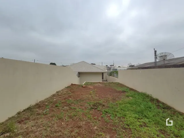 Parede alta de uma propriedade com grama seca no primeiro plano.