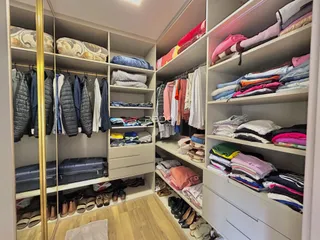 Vista interna de um armário com roupas e móveis em um imóvel.