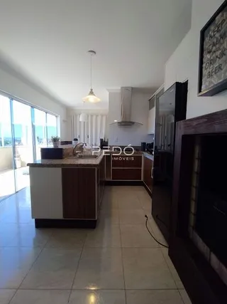 Vista interna de uma sala com grandes janelas e área de cozinha.