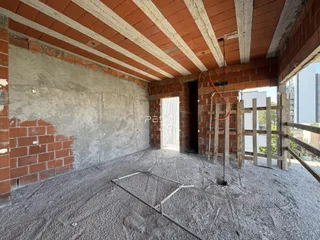 Interior de um espaço em construção com paredes de tijolo aparente e piso de concreto.