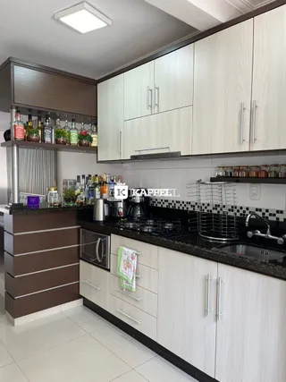 Cozinha moderna com armários brancos e bancadas escuras.