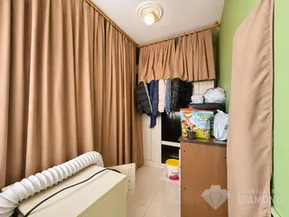 Quarto com cortinas bege e roupas penduradas.