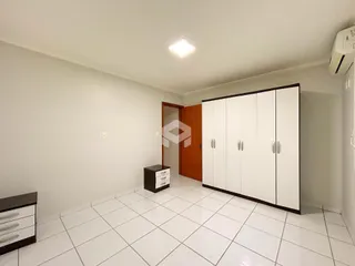 Ambiente interno de uma sala com piso de cerâmica e armários brancos.