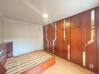 Quarto com cama de madeira e armário embutido na parede.
