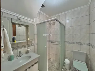 Foto interna de um banheiro com revestimento cerâmico e box de vidro.