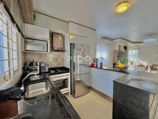 Vista da cozinha moderna com armários brancos e bancadas escuras.