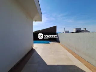 Vista externa mostrando uma área de piscina com piso de porcelanato e muro de contenção.