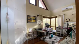 Sala de estar com piso de madeira e grandes janelas no interior de uma residência.