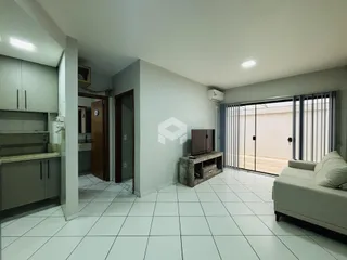 Sala de estar com cozinha e porta de vidro abrindo para o exterior.