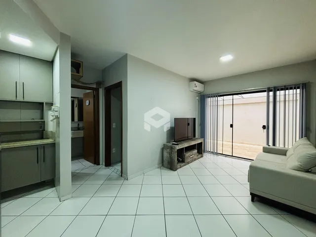 Sala de estar com cozinha e porta de vidro abrindo para o exterior.